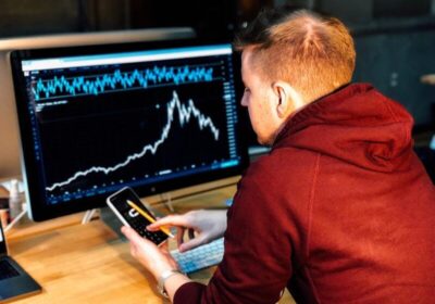 Blog Man holding smartphone with monitor displaying trends